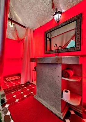 a red bathroom with a sink and a mirror at Private Luxury Camp in Merzouga