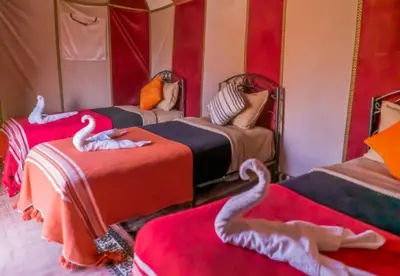 a room with three beds with swans on them at Private Luxury Camp in Merzouga