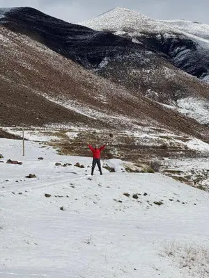 a person standing in the snow with their arms up at Dar Ayoub in Inlghdene