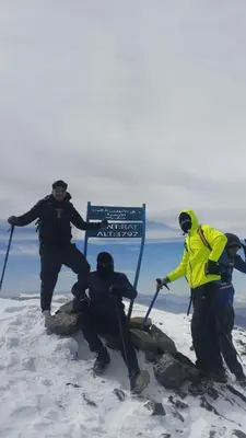 three people standing on top of a sign in the snow at Dar Ayoub in Inlghdene