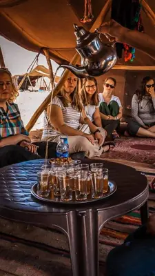 a group of people sitting around a table with glasses on it at Magnifique Luxury Camp in Merzouga