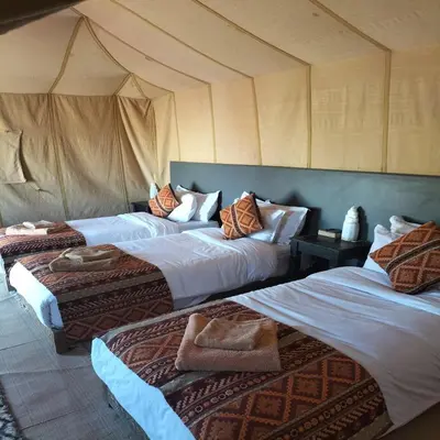 a bedroom with three beds in a tent at Magnifique Luxury Camp in Merzouga