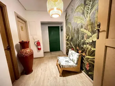 a hallway with a couch and a wall with a plant mural at Maison d 'Hôtes de Charme 7 Ch in Sidi Bouzguia