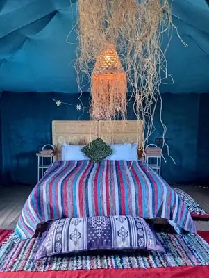 a bedroom with a bed with a colorful comforter at Tenere desert luxury camp in Merzouga