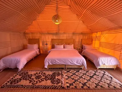 a bedroom with two beds in a large room at Tenere desert luxury camp in Merzouga