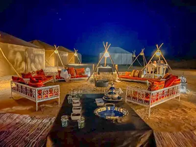 a tent with a table in the desert at night at Tenere desert luxury camp in Merzouga