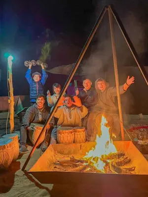 a group of people sitting around a fire at Tenere desert luxury camp in Merzouga