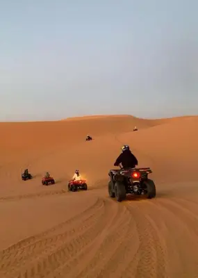 a group of people riding on atvs in the desert at Tenere desert luxury camp in Merzouga