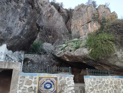 a building with a stone wall next to some rocks at Gite touristique bouknala in Abinane