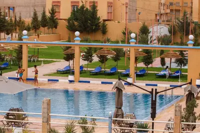 a pool in a resort with people playing in it at Palmiers Hôtel Club in Er Rachidia