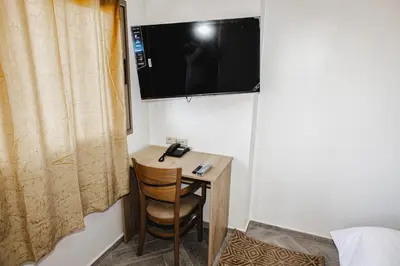 a room with a small desk with a television on the wall at Palmiers Hôtel Club in Er Rachidia