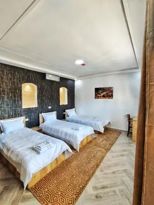 two beds in a room with a wall at Palmiers Hôtel Club in Er Rachidia