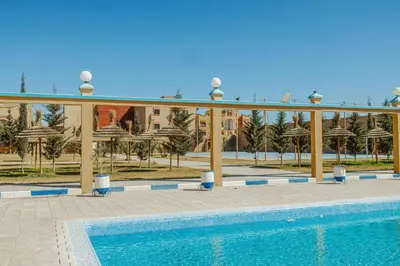 a resort with a swimming pool and a building at Palmiers Hôtel Club in Er Rachidia