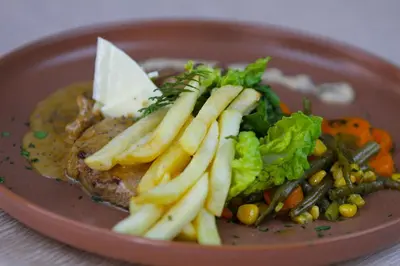 a plate of food with french fries and vegetables at Palmiers Hôtel Club in Er Rachidia