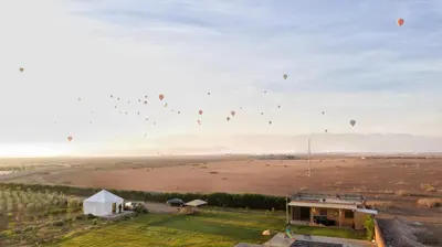 a group of hot air balloons flying over a field at Getaway between nature and adventure in Marrakech
