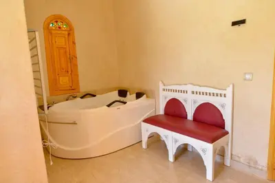 a bathroom with a tub and a stool and a chair at Jnane az Zatr Villa and pool Ourika in Ourika