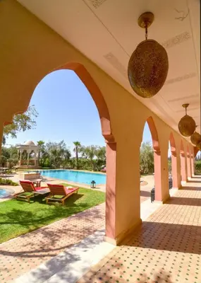 a building with an archway and a swimming pool at Jnane az Zatr Villa and pool Ourika in Ourika