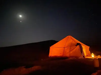 an orange tent in the middle of a field at night at Dar Mustapha&Linda GmbH desert-inspiration in Ksebt Ibourri