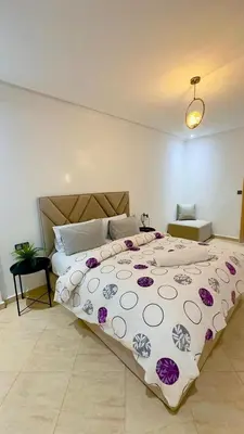 a bedroom with a large bed with purple flowers on it at Appartement de luxe à khouribga in Khouribga