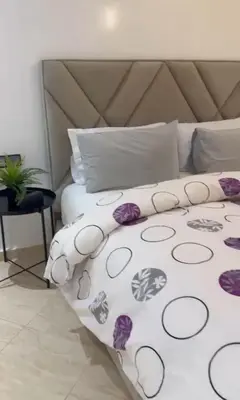 a white bed with purple flowers on it at Appartement de luxe à khouribga in Khouribga
