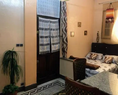 a bedroom with a bed and a table and a door at Tisra Appartement in Meknès