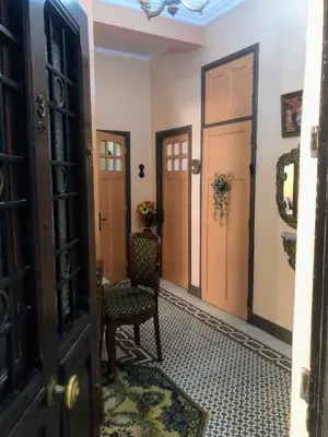 a hallway with two sets of doors and a chair at Tisra Appartement in Meknès