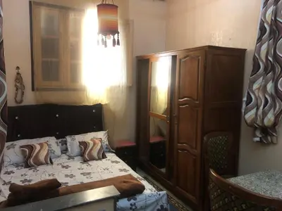 a bedroom with a bed and a wooden cabinet at Tisra Appartement in Meknès