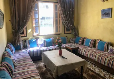 a living room with couches and a table and a window at Tisra Appartement in Meknès