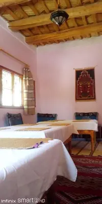 a bedroom with three beds and a wooden ceiling at Hotel Source De Dades in Boumalne