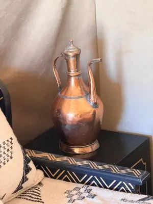 a copper vase sitting on top of a table at Amrad luxury camp in Merzouga