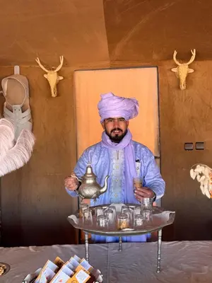 a man holding a serving tray with a kettle at Amrad luxury camp in Merzouga
