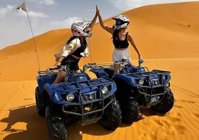 two people riding on atvs in the desert at Amrad luxury camp in Merzouga