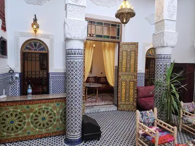 a room with two beds and a table in a building at Dar Zerbtana suite Kenza in Fès