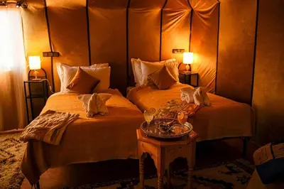 a hotel room with two beds and a table at Merzouga Experience Camp in Merzouga
