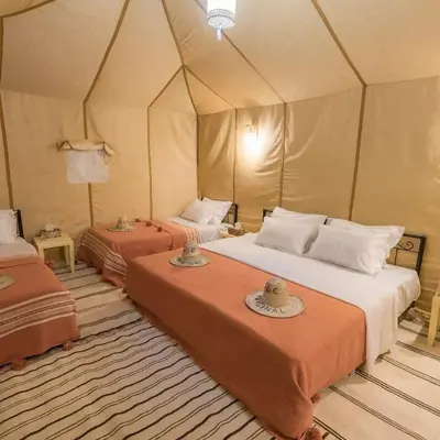a bedroom with two beds in a tent at Merzouga Experience Camp in Merzouga