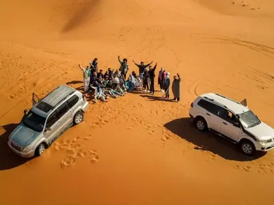 a group of people standing in the sand in a desert at Merzouga Experience Camp in Merzouga