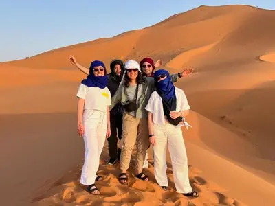 a group of people standing in the desert at Merzouga Experience Camp in Merzouga