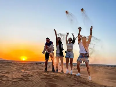 a group of people jumping in the sand on the beach at Merzouga Experience Camp in Merzouga