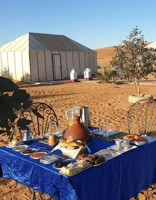 a blue table with food on it in the desert at Merzouga Erg Merzouga Camp in Merzouga