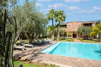 a swimming pool with lounge chairs and a house at Villa Layyine avec personnel, piscine, spa et sports in Marrakech