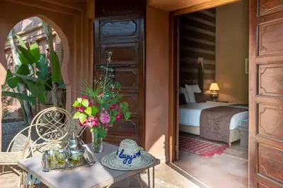 a room with a bed and a table with flowers at Villa Layyine avec personnel, piscine, spa et sports in Marrakech