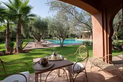a table and chairs on a patio with a pool at Villa Layyine avec personnel, piscine, spa et sports in Marrakech