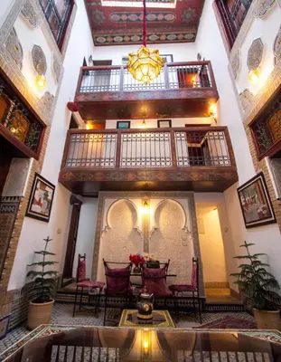 a room with a table and chairs in a building at Dar Bab jdid fez in Fès
