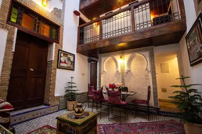 a room with a table and chairs and a balcony at Dar Bab jdid fez in Fès