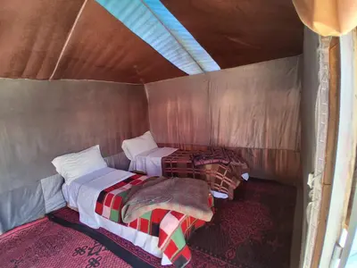 a small room with two beds in it at Desert Tigmi Camp in Merzouga