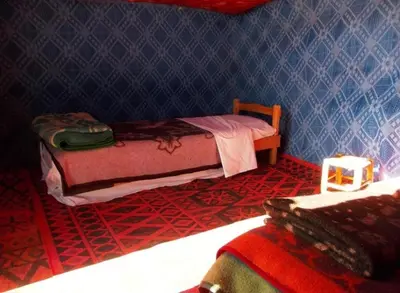 a bedroom with two beds and a blue wall at Desert Tigmi Camp in Merzouga