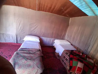 a room with two beds in a tent at Desert Tigmi Camp in Merzouga
