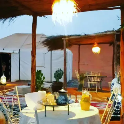 a patio with a table and chairs and a tent at Desert Tigmi Camp in Merzouga