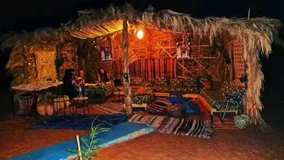 a room with a large straw hut with people in it at Desert Tigmi Camp in Merzouga