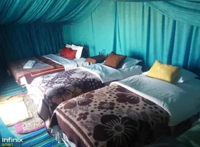 three beds in a room with blue walls at Desert Tigmi Camp in Merzouga